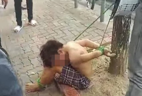 Bé trai bị trói vào gốc cây. Ảnh: Cắt từ video.