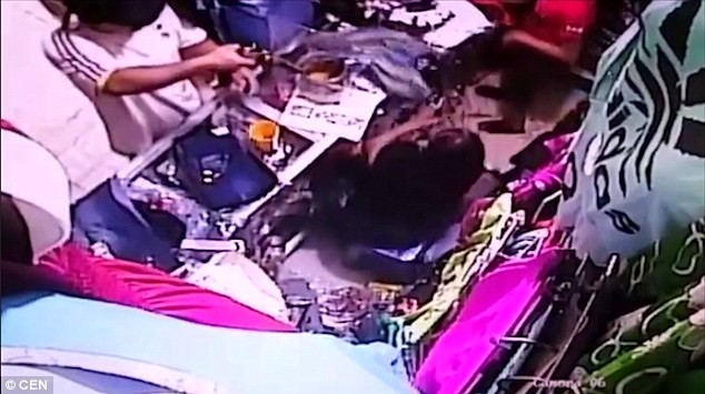 Tên cướp chĩa súng vào đầu người phụ nữ.