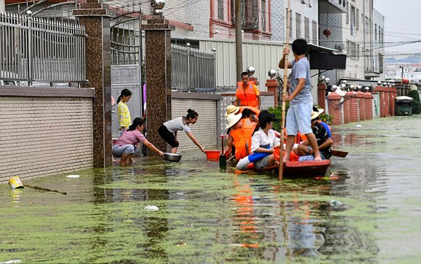 Tình trạng mưa lớn gây ngập lụt khắp nơi, khiến người dân phải di chuyển bằng thuyền bè. Ảnh: Rex.