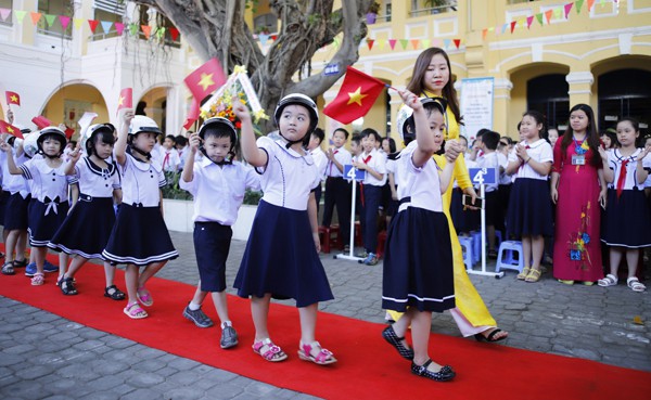 
Sáng nay Đà Nẵng nắng nhẹ. Hơn 500 học sinh lớp 1 ở Trường Tiểu học Phù Đổng đội mũ bảo hiểm, cầm lá cờ Tổ quốc, được các anh chị khối lớp 4, 5 chào đón vào trường bằng nhưng chàng pháo tay. Nhiều em nhỏ đi chưa theo hàng lối, mặt còn ngái ngủ. Ảnh: Nguyễn Đông (VnExpress)
