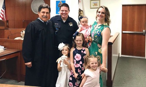 Gia đình cảnh sát Jesse Whitten chụp ảnh cùng luật sư (ngoài cùng bên trái) sau khi hoàn tất thủ tục nhận nuôi Harlow (bé gái đang được bế) hôm 30/8. Ảnh: ABC.