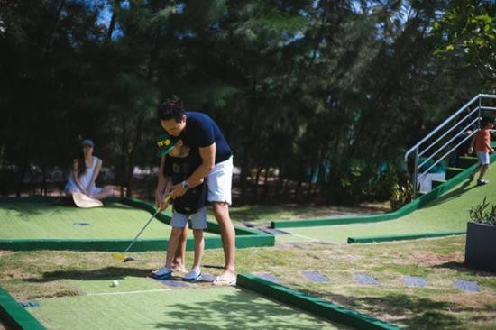 Kim Lý hướng dẫn Subeo chơi golf trong khi Hồ Ngọc Hà lặng lẽ ngồi nhìn từ xa.