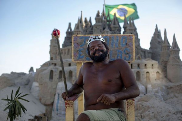 Marcio Mizael Matolias, 44 tuổi, không tốn tiền thuê nhà sau 22 năm sống trong một lâu đài cát bên bãi biển Rio de Janeiro, Brazil. Trong ảnh, Marcio ngồi trên ngai vàng chụp ảnh trước tòa lâu đài của mình, tay cầm quyền trượng.
