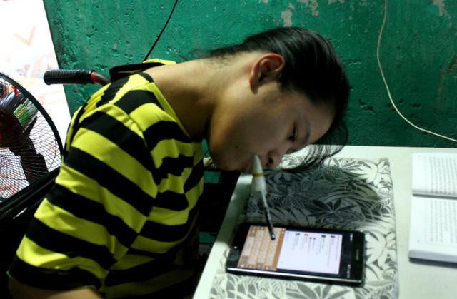 Hương ngậm bút gõ chữ trên máy tính bảng để tương tác với mọi người trên mạng xã hội. Ảnh Kim Bảo Ngân