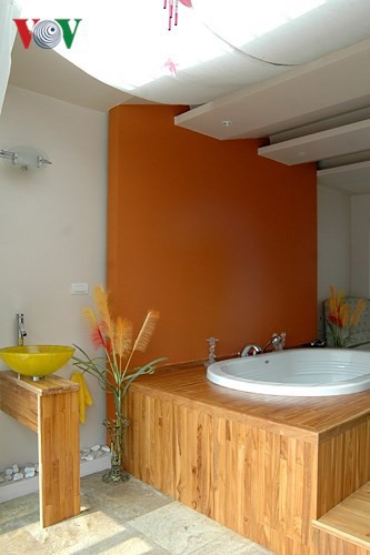 Phòng tắm thư giãn với bồn sục đặt trên bệ gỗ, tường được sơn thay vì ốp gạch như thông thường; cho cảm giác ấm cúng.
