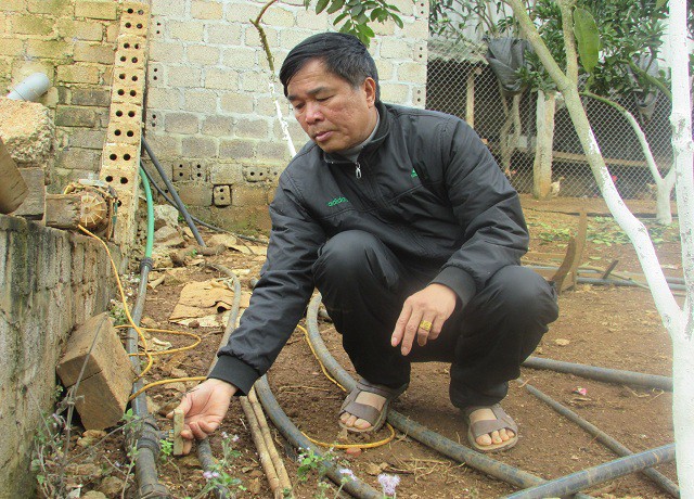 Ông Dũng đang bật hệ thống nước để tưới tiêu cho vườn cây ở trang trại