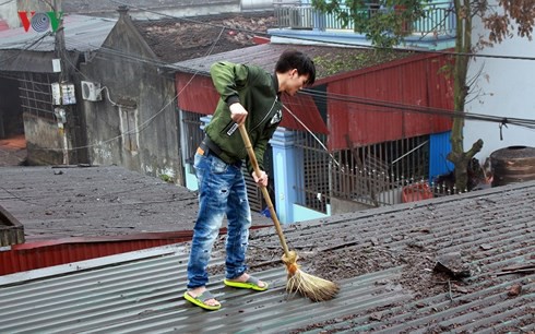 
​Một người dân thôn Quan Độ quét những viên đạn vương vãi trên mái nhà mình sau vụ nổ.
