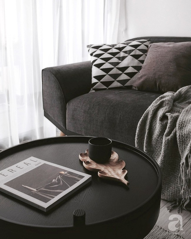 Chiếc bàn trà màu đen ấn tượng, tạo sự liên kết sắc màu ăn ý với khung tranh trên tường và công tắc điện.