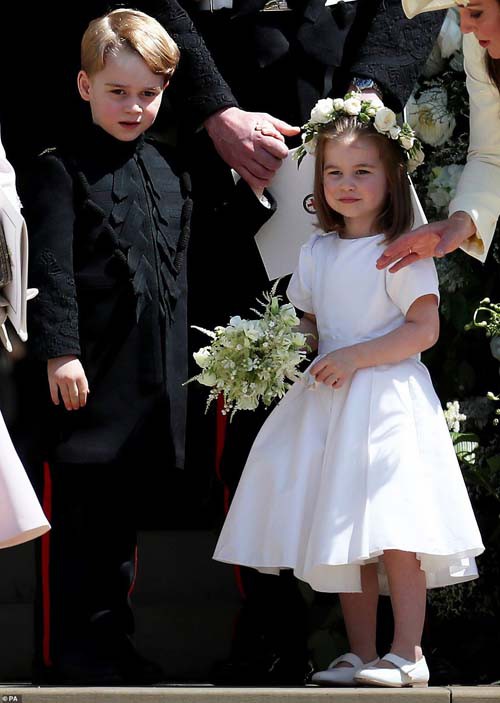 Ở đám cưới Hoàng tử Harry, Hoàng tử George trông bảnh bao khi diện áo dáng dài màu đen, kết hợp quần cùng màu, trong khi Công chúa Charlotte như thiên thần với bộ váy trắng, đeo vòng hoa và cầm bó hoa nhỏ xinh trên tay.