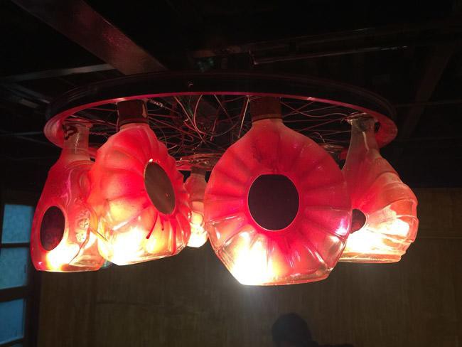 Đèn chùm được kết hợp từ chiếc vành bánh xe và những vỏ chai rượu cũ.