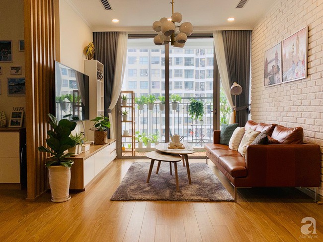 Khu vực phòng khách ấm cúng với tông vàng trầm của gỗ, nâu của sofa và điểm tô bởi màu xanh tươi của cây cỏ.