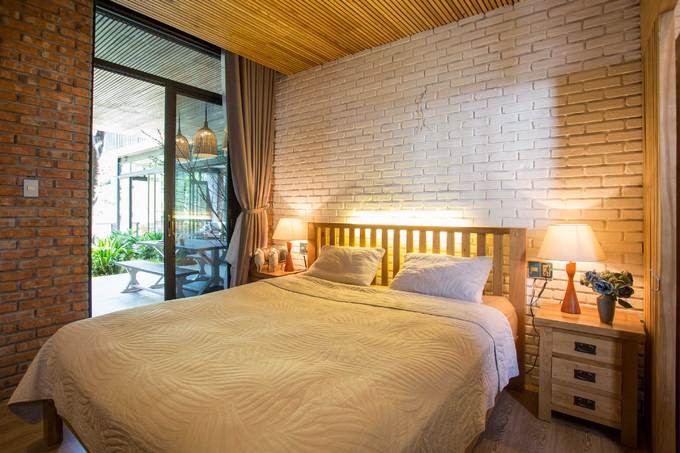 Ngoài ra, ở tầng trệt còn có một phòng ngủ, kết nối với sân vườn bên ngoài bằng cửa kính trượt. Khi mở toàn bộ cửa kính, không gian trong nhà và sân vườn như hoà vào làm một, giúp chủ nhà tận hưởng được không gian rộng rãi và thiên nhiên núi rừng.