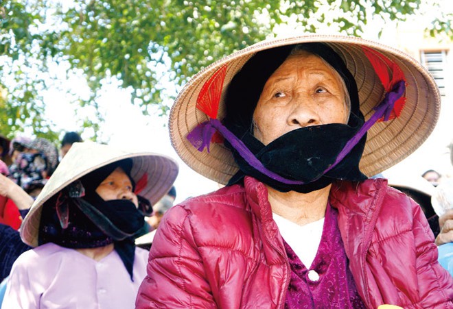 Khán giả cao tuổi bịt mặt xem hát đúm ở sân đình. Ảnh: LQP