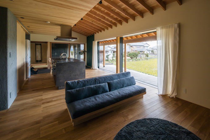 Phòng khách gần như trống trơn với chiếc ghế sofa và một tấm thảm thể hiện rõ phong cách tối giản.