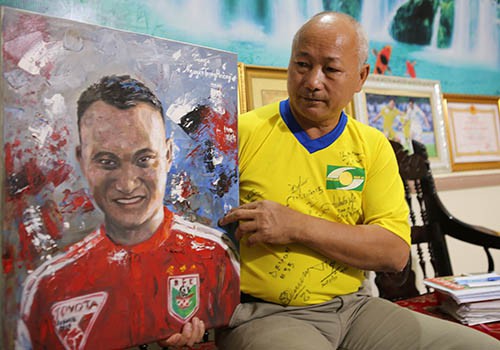 
Ông Nguyễn Trọng Hường bên bức tranh cổ động viên vẽ tặng Trọng Hoàng, con trai ông. Ảnh: Nguyễn Hải.
