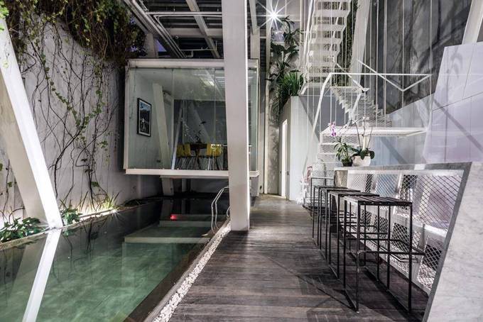 Cạnh bể bơi là một quầy bar chạy dài. Cũng ở tầng một còn có một phòng làm việc như một chiếc hộp kính nhỏ được treo lơ lửng trên hồ bơi.