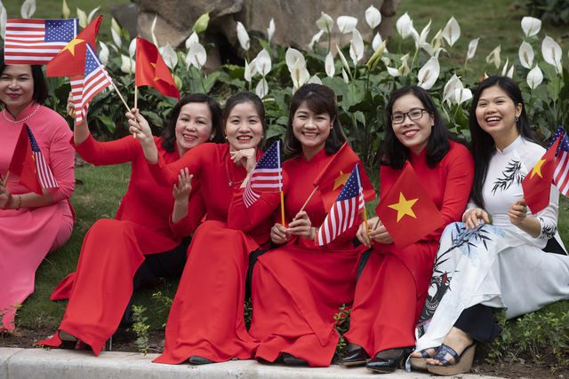 Những phụ nữ chào đón đoàn xe của ông Trump tới Phủ Chủ tịch với tà áo dài Việt Nam cùng nụ cười tươi tắn.