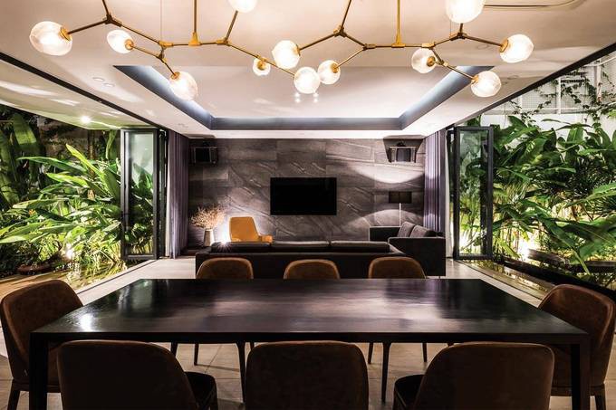 Ngoài bộ đèn chùm và lọ hoa nhỏ, không gian tầng một không có bất kỳ đồ trang trí nào. Hai vườn cây phía trước và sau nhà đóng vai trò như hai bức tranh phong cảnh tô điểm không gian.