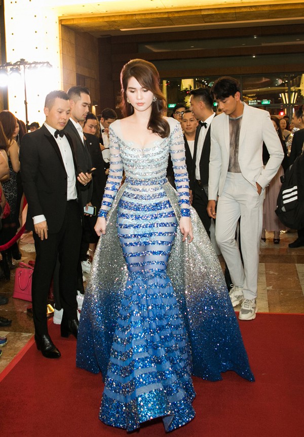 Thảm đỏ Đêm hội chân dài 12 vào tối 9/3 tại Singapore thu hút hàng chục ngôi sao của showbiz Việt tham dự. Nữ hoàng nội y Ngọc Trinh là tâm điểm của ống kính với bộ cánh đính kết nổi bật, khoe trọn được ba vòng gợi cảm. Cô bay sang quốc đảo sư tử từ hai ngày trước để đồng hành cùng ông bầu Vũ Khắc Tiệp trong mọi hoạt động.