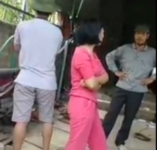 Bùi Thị Kim Thu (mặc đồ ngủ màu hồng) và Cầm Văn Chương (đội mũ bảo hiểm) nói chuyện với một số người nhằm tưng hoả mù. Ảnh cắt từ clip