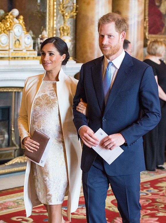 Meghan kín đáo khoe bụng bầu trong chiếc váy họa tiết hoa được đặt may riêng và áo khoác Amanda Wakeley gần 1.200 USD. Bà bầu 7 tháng búi tóc thấp đặc trưng, đi giày cao gót da lộn màu nude của Paul Andrew giá 690 USD và cầm clutch satin của Wilbur & Gussie giá 270 USD. Ảnh: PA.