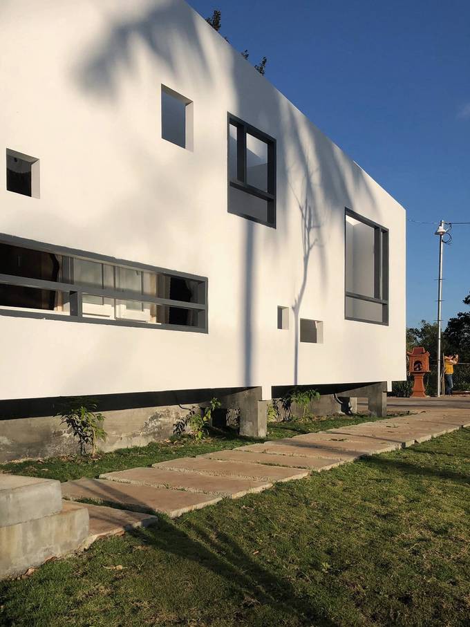 Lối đi với các bậc đá trên thảm cỏ xanh, giống như đường ray tàu, dẫn đến bậc tam cấp để vào nhà. Không gian hướng hồ được cách điệu theo kiểu nhà sàn càng khiến ngôi nhà nổi bật.