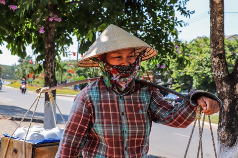 Người phụ nữ gánh hàng rong dưới bóng cây tại các vỉa hè nhằm tránh cái nắng gay gắt.