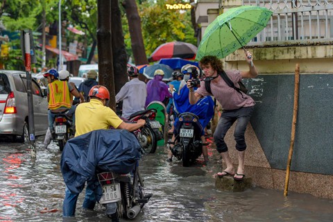 Chuẩn bị sẵn cả ô để tác nghiệp, Joanik (Pháp) miệt mài chụp ảnh người dân bì bõm dưới nước.