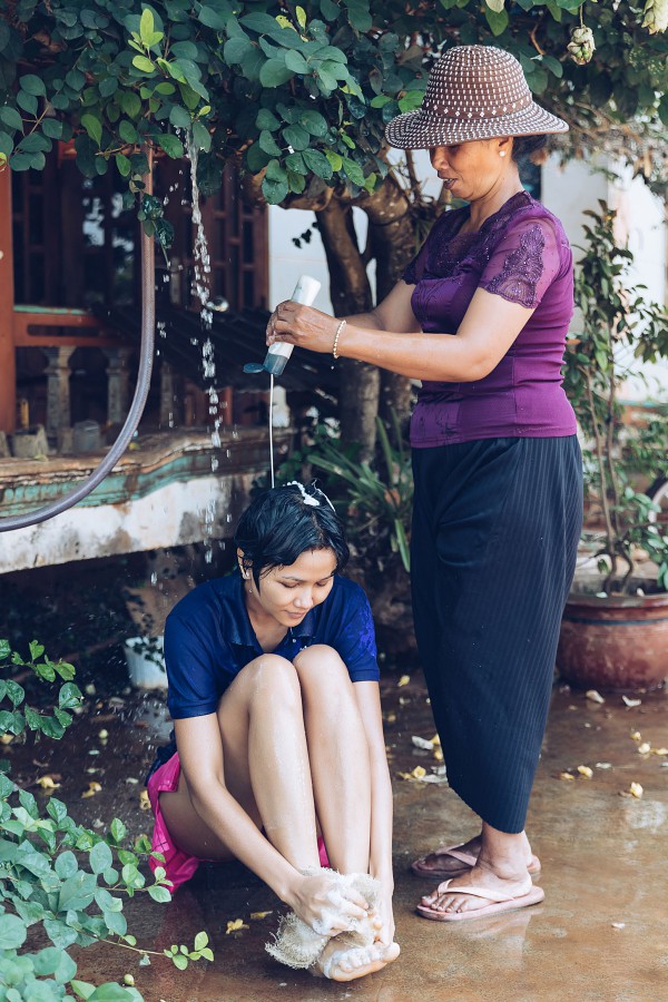 Trong một chuyến thăm quê gần đây, HHen Niê thích thú được mẹ tắm gội bên góc sân nhà.