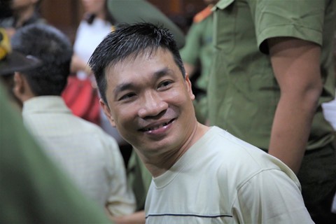 
Văn Kính Dương cười tươi khi được dẫn giải đến tòa ngày 7/5. Ảnh: Lê Quân.
