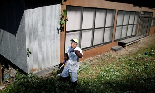 
Một người dân dọn vườn của một ngôi nhà bỏ hoang gần thủ đô Tokyo. Ảnh: Reuters.
