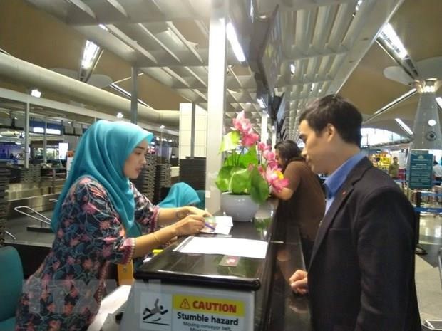 Cán bộ Đại sứ quán Việt Nam hỗ trợ làm thủ tục check-in cho Đoàn Thị Hương lên tàu bay từ Kuala Lumpur về Hà Nội. Ảnh: TTXVN.