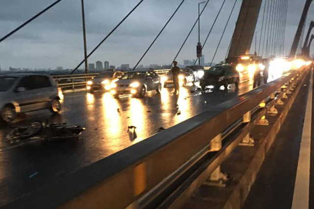 Phóng xe máy ngược chiều trên cầu Nhật Tân, 2 thanh niên tông thẳng xe taxi - Ảnh 1.