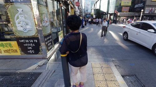 An elderly woman stands at a small, bustling plaza in front of the Piccadilly theater in Seoul, South Korea, a a place where elderly prostitutes openly solicit customers for sex in nearby motels.