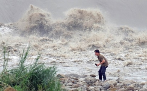 A man battles to stand up beside the Xindian river as Typhoon Dujuan continues to batters Taipei on Tuesday morning. Photo: AFP