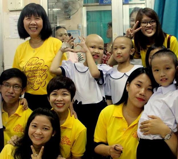 Cô Kim Phấn (đứng, bìa trái), các tình nguyện viên và lớp học “trọc đầu”. Ảnh: Tuổi Trẻ.