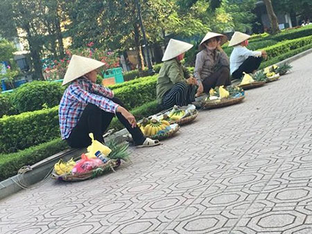 4 người nữ gánh hàng rong tập trung ngồi thành một hàng chờ khách du lịch