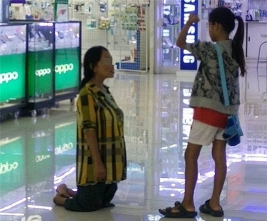 Bức ảnh bà mẹ tàn tật quỳ trước mặt con gái gây phẫn nộ trên mạng Internet Thái Lan.
