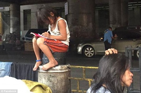 Bé gái Cielo Gonzales ngồi trên bục chắn đường mải mê làm bài tập. Ảnh: Facebook