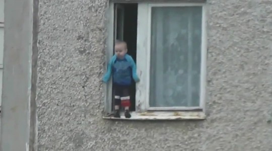 Bé trai đứng trên gờ tường cửa sổ tầng 8 chơi đùa mà cha mẹ không phát hiện. Ảnh: RT
