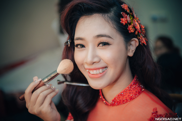 Cùng với gương mặt rạng ngời, chuyên gia makeup làm tóc xoăn nhẹ nhàng và tô điểm mái tóc bằng chiếc cặp đính pha lê màu đỏ ton sur ton cùng màu áo dài.