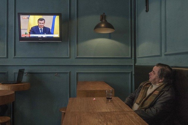 Một người dân Kiev (Ukraine) xem TV trong khi nhâm nhi chút rượu.