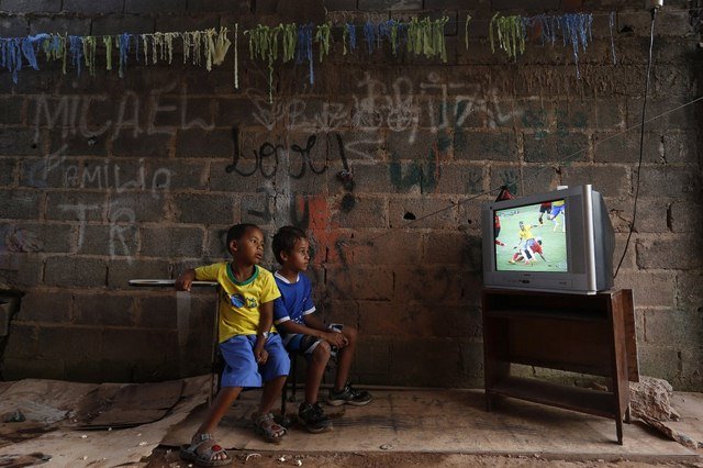 Mấy cậu bé chăm chú theo dõi bóng đá trong mùa World Cup ở ngoại ô thủ đô Brasilia (Brasil) trong trận đấu giữa Brasil và Mexico.