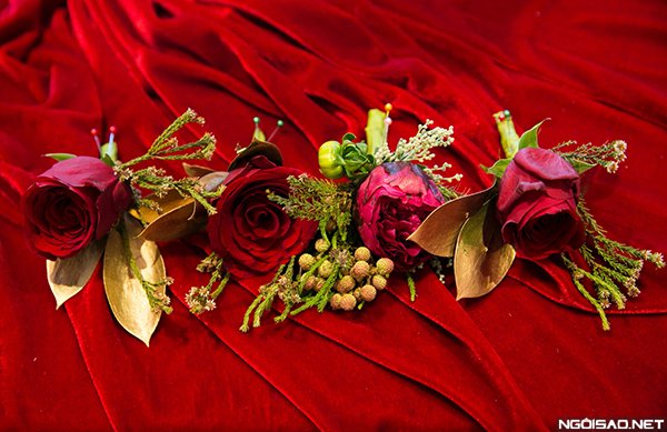 Hoa cài áo của chú rể là bông mẫu đơn đồng điệu cùng hoa cô dâu, trong khi đó, hoa cài áo cho các phù rể là hồng nhung sang trọng.