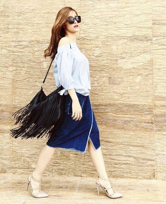 Cũng với chân váy denim xẻ nhưng Đông Nhi lại khá phong cách khi diện cùng áo trễ vai và túi xách tua rua thời thượng đi cùng.