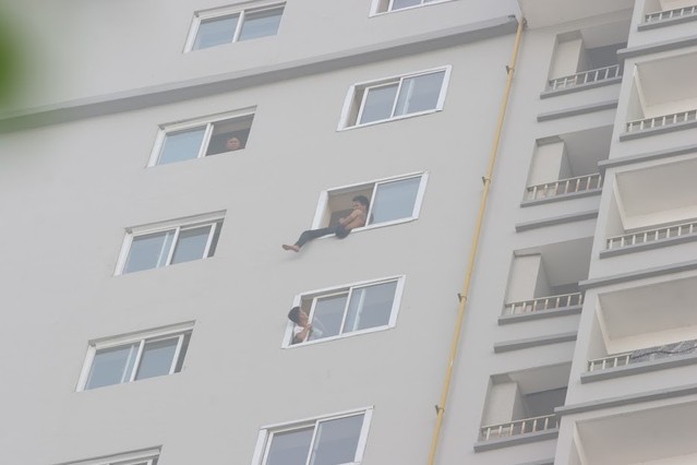 Người thanh niên ngồi vắt vẻo ở cửa sổ chung cư.