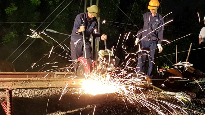 
Công nhân cắt ghép thanh ray cuối cùng trước khi hoàn thành phần kỹ thuật của cầu Ghềnh mới khuya 24/6. Ảnh: Phước Tuần
