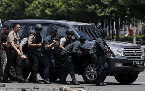 Cảnh sát Indonesia nấp sau một xe ô tô tại hiện trường đấu súng với nghi phạm khủng bố. Ảnh: Reuters.