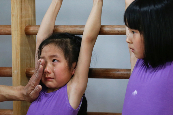 
Tại trường đào tạo các vận động viên trẻ nghiệp dư Yangpu ở Thượng Hải, những đứa trẻ, nhỏ nhất là 6 tuổi, đang tuân thủ một chế độ tập luyện nghiêm khắc vì mục tiêu đạt được huy chương vàng ở các kỳ thế vận hội Olympic. Trong ảnh, huấn luyện viên lau nước mắt cho một bé gái khi cô bé bị mệt mỏi do phải tập động tác khó.
