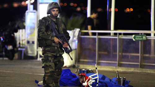 
Một binh sĩ Pháp đứng cạnh thi thể một nạn nhân tại hiện trường vụ tấn công bằng xe tải ở thành phố Nice. Ảnh: AFP
